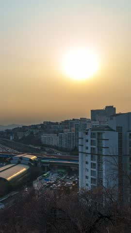 Vertical aerial hyperlapse of bustling traffic on Gangbyeonbuk-ro expressway and Dongho Bridge with sun disk setting over Hannam district in Seoul South Korea