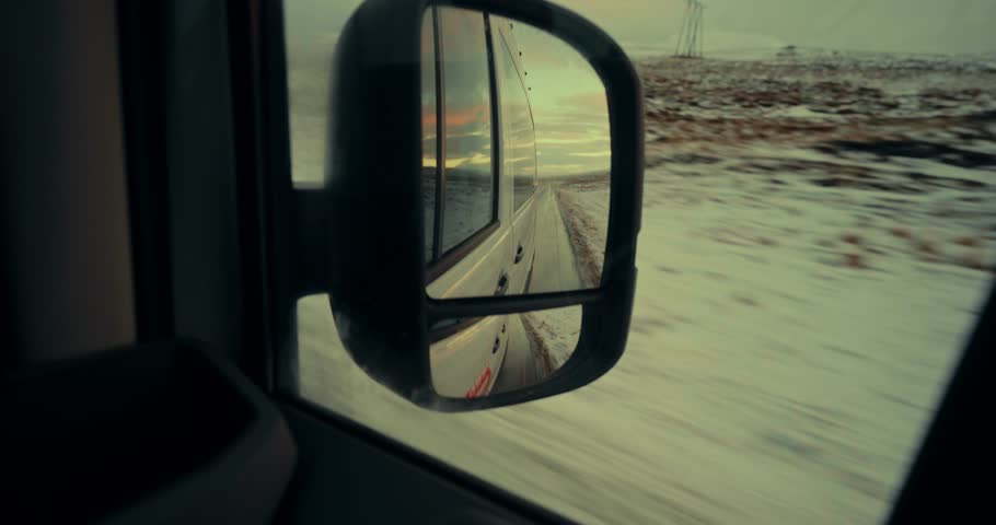 Rear View Mirror Reflection of a Van Driving on a Snowy Road in Iceland Landscape