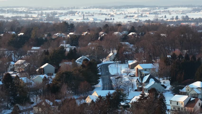 Winter wonderland in quiet snowy housing area of America. Aerial wide shot. Sunset time in rural suburb neighborhood of USA. Panorama view.