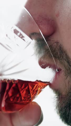 Close-up man drinking alcohol from glass, concept of addiction. Vertical video.