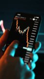 Close up of smartphone with candlestick chart on trading app screen. Mobile investment, cryptocurrency trading and financial market analysis concept in low light. - Powered by Shutterstock - Get 15% off with code: PIKWIZARD15