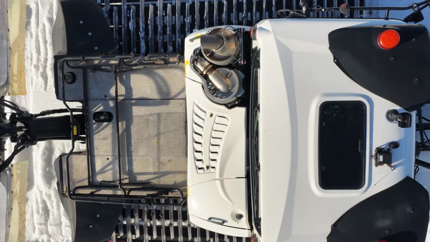 Snow grooming machine preparing ski slope near Zakopane with chairlift and Tatra Mountains in background, winter resort scene showing piste maintenance, alpine landscape and clear sunny day	
