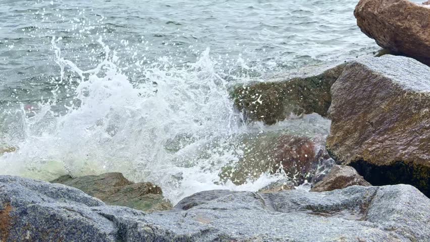 Sea wave splashing against a rocky shore in Barcelona, Spain