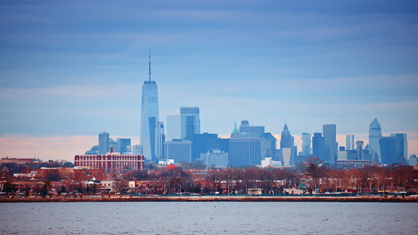 Lower Manhattan skyline view with One World Trade Center. Wide shot of New York City financial district skyline across the river under overcast sky.