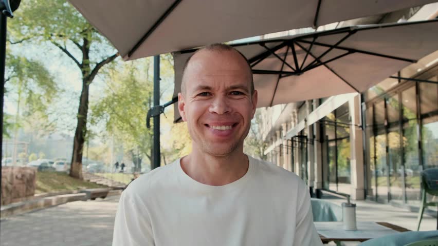 A middle-aged man with short hair smiles warmly at the camera. Perfect 4K video for lifestyle, portrait, and positive emotions content.