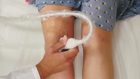 Ultrasound examination on patient knee in medical clinic. Rehabilitation, medical care, and physiotherapy. Doc performing ultrasound examination of leg veins behind knee. vascular procedure. 4 k video - Powered by Shutterstock - Get 15% off with code: PIKWIZARD15