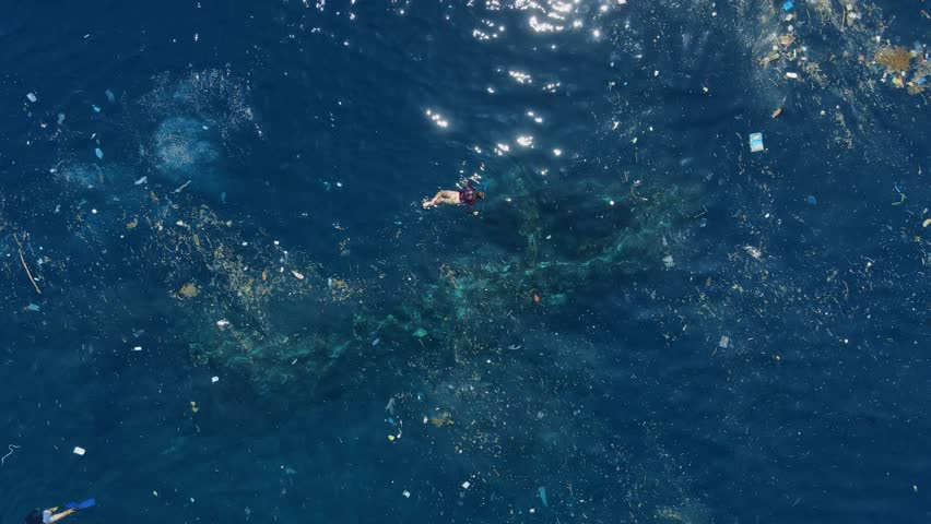 People swimming in dirty ocean with floating plastic pollution. Above view