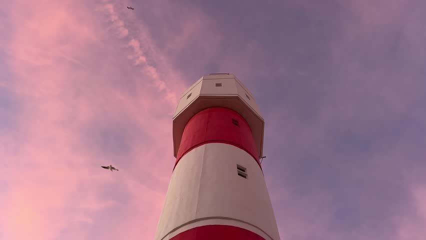 low-angle shot looking up at a tall, majestic lighthouse against a beautiful sunset sky