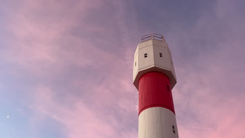 shot looking up at a tall, majestic lighthouse against a beautiful sunset sky