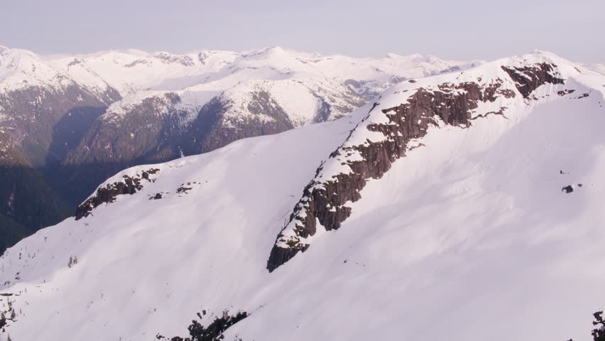 Aerial view of a stunning snowy mountain landscape showcasing majestic peaks and valleys. The scene captures the serene beauty of nature in a tranquil setting.
