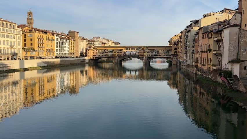 View of the Arno River in Florence, Italy, with the historic Ponte Vecchio bridge spanning across it.