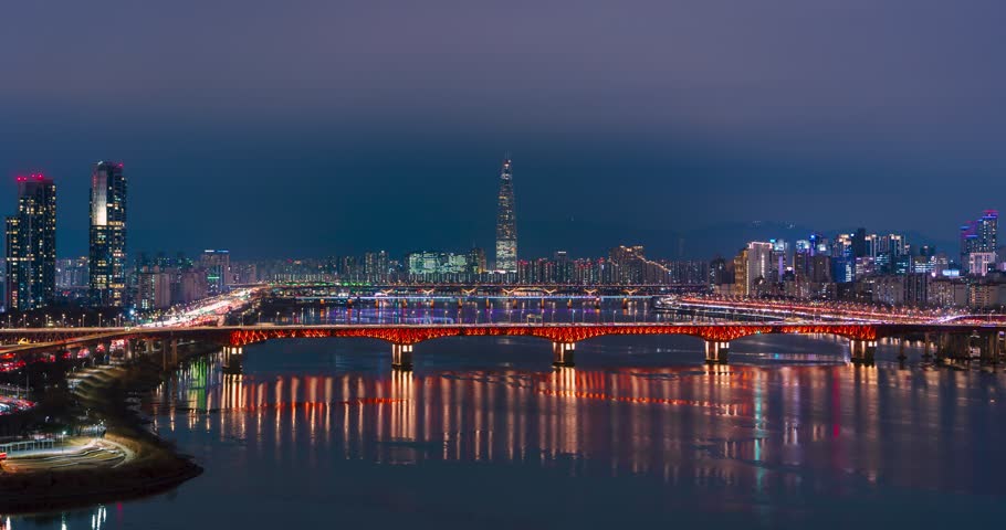 Seoul, South Korea - time lapse, Seongsu Bridge illuminated orange, Gangbyeonbuk-ro expressway traffic light trails, Lotte Tower skyline, Han River reflections, blue hour winter night