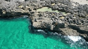 Smooth aerial glide over wave-fed coastal rock pool with bright sunlight and clear water - Powered by Shutterstock - Get 15% off with code: PIKWIZARD15