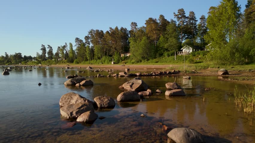 Näs Sannar Strand, Lake Vänern, Sweden — low altitude flyover, shallow water, rocks, sandy shore, pine forest, cottages, golden hour light