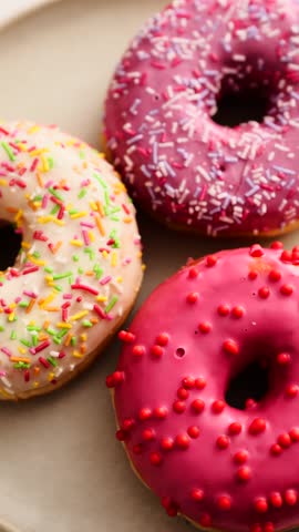 Brightly colored donuts with sprinkles arranged on a round plate in a well-lit setting