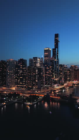 Aerial view of Chicago Illinois at night reveals glowing marina, curving highways, river reflections, and illuminated downtown skyline, capturing modern city motion, travel mood, and urban scale