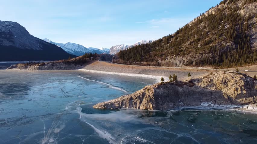 Aerial Abraham Lake Rocky Outcrop and Mountain Winter Landscape Flyover. 3D Illustration