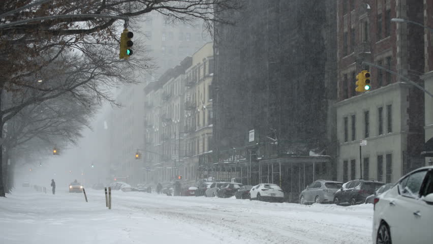 Street in Upper Manhattan during snowstorm with one cab moving slowing in snow
