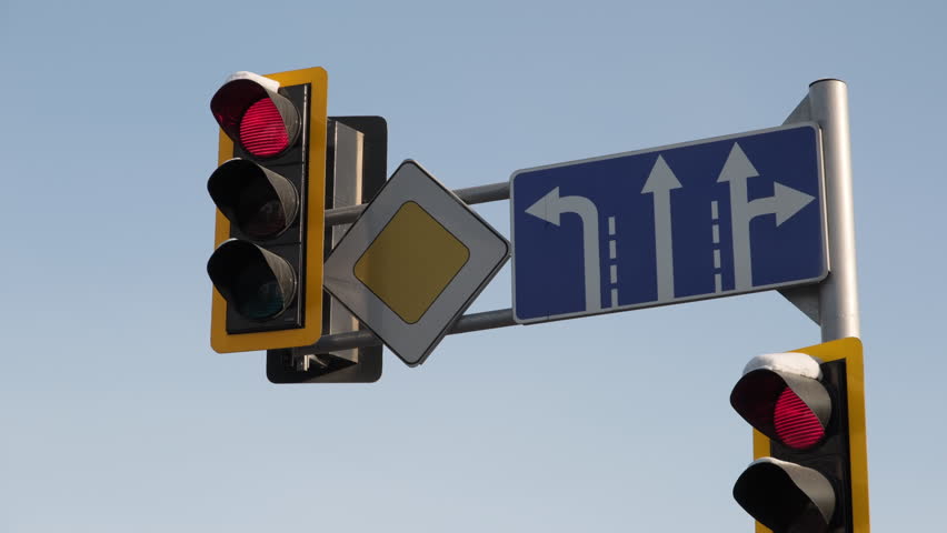 Traffic light changing signals and road signs on pole against background blue sky, regulation movement of vehicles and pedestrians