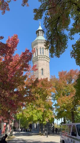 Personal point of view while walking toward the historic Highbridge Water Tower surrounded by trees in the fall in Highbridge Park, Washington Heights