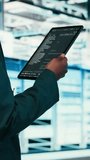 Vertical video Close up of data center programmer using tablet app to write code, futureproofing company network. Woman walks in server room with programming script on device to increase cybersecurity - Powered by Shutterstock - Get 15% off with code: PIKWIZARD15