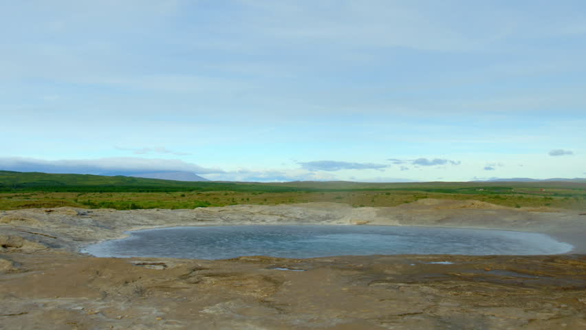 Boiling water and steam rising from a geothermal hot spring in a volcanic landscape in Iceland