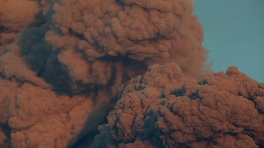 Plume of ash and smoke rising from an erupting volcano in Iceland against a clear blue sky