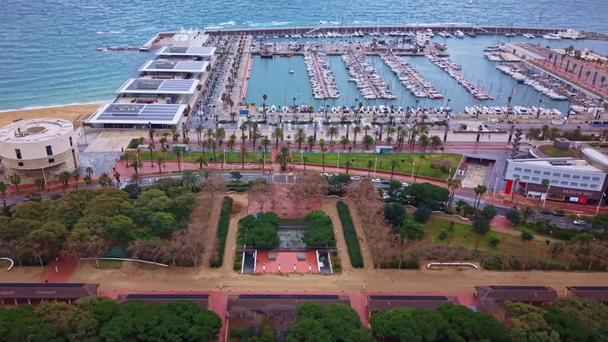 Approaching drone fly toward the Barcos de Barcelona marina filled with yachts and boats along Mediterranean Sea coastline, Barcelona, Spain