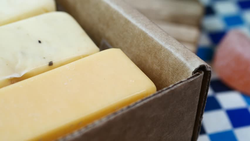 Close up cinematic footage of various cheese bars in paper box ready for sale at market, gourmet food dynamic shot