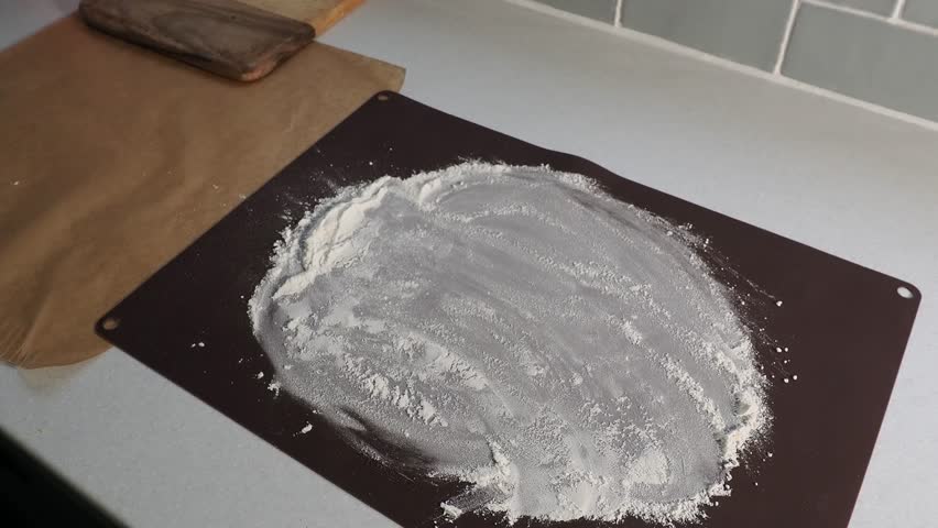 Putting homemade bread with sourdough onto floured sheet in the kitchen.