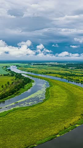 Drone view of lush river bend under cloudy sky, serene and expansive feel