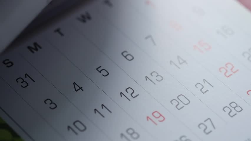 Close up video of turning pages of calendar, flipping through desk calendar, time passing, day, week, month, date