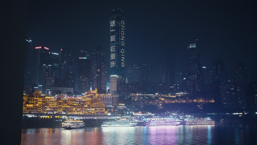 night view of Chongqing World Financial Center with CHONGQING signage beside brightly lit Hongyadong complex and cruise ships on Jialing River waterfront