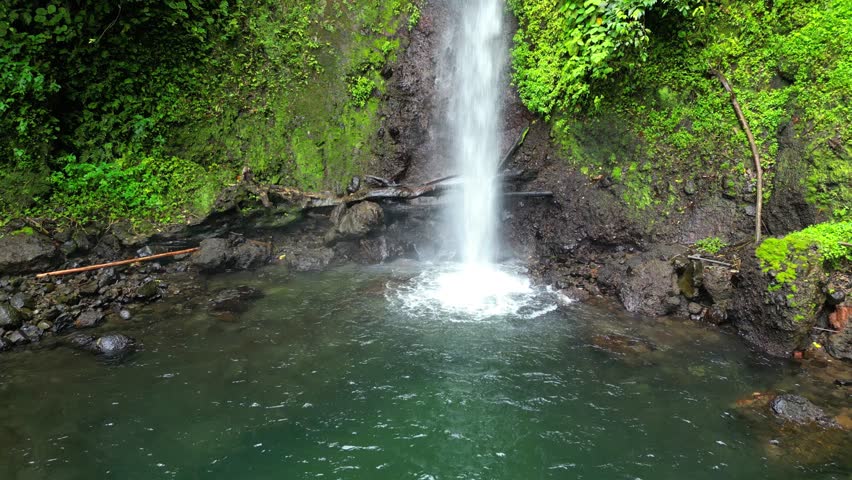 View of water of Bombaim waterfall over the rocks amidst the magnificent, untouched, and lush green forest.São Tomé,Africa