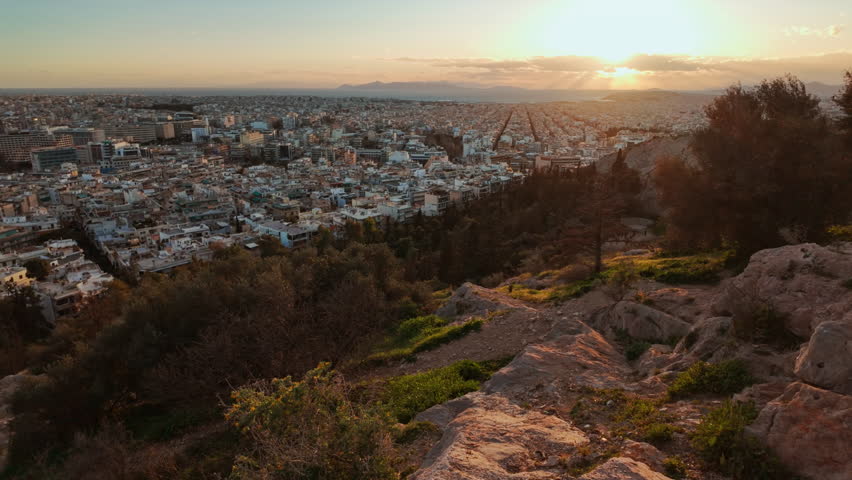 Panoramic cityscape from a hilltop viewpoint with dense rooftops and soft evening light over Athens, Greece
