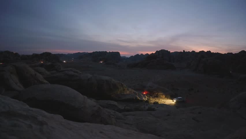 Aerial view over Petra surrounding mountains at dusk highway traffic light trails crossing desert valley night timelapse Jordan