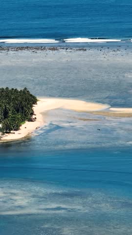 Tropical Island with white sandy beach. Boats over the blue sea and waves. Mindanao, Philippines. Vertical, stories.