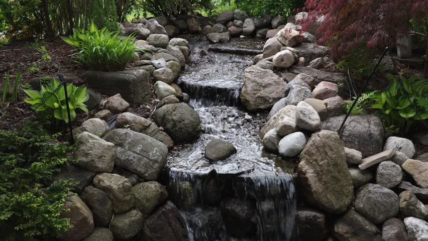 Garden waterfall with stones and ornamental plants. Ornamental Gardens in Ottawa, Canada