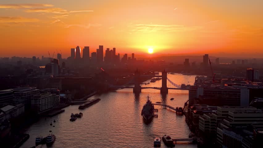 Aerial sunrise view of the cityscape of London, UK, with Tower Bridge, river Thames and the silhouette of Canary Wharf in the background