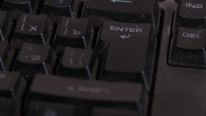 Finger hitting the Enter key on a dirty used keyboard, technology and workspace concept.