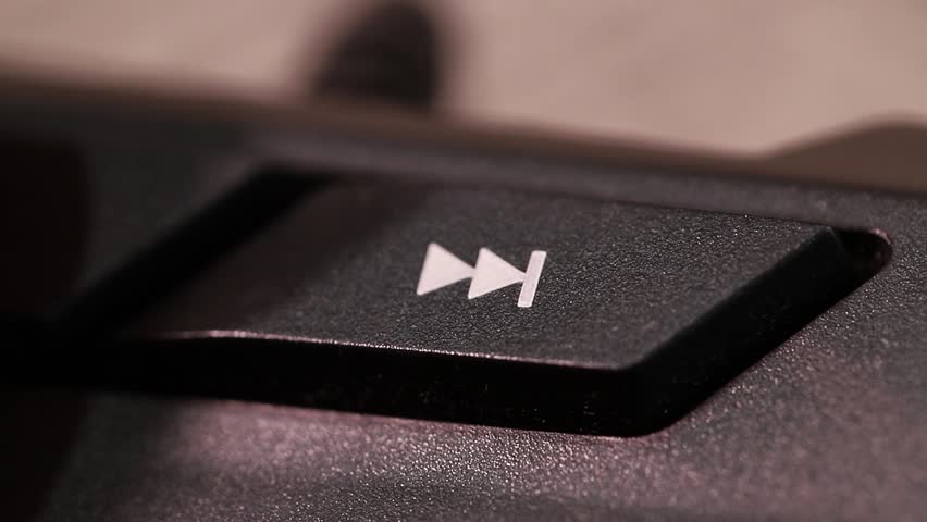 Skipping to the next song or video on a computer keyboard, macro shot of human finger clicking forward button
