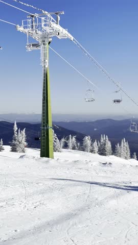 A snowy ski slope with cables and chairs under a clear blue sky, showcasing the winter sports area in the mountainous landscape in Sheregesh