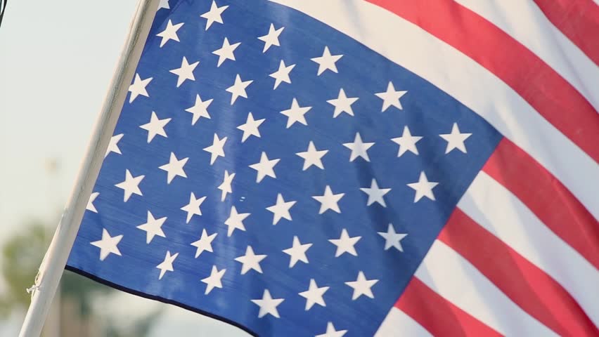 A beautifully fluttering American flag at sunset. Close-up in real time. Patriotic national symbol of unity and freedom. Flag Day, American holidays, Independence Day, July 4th