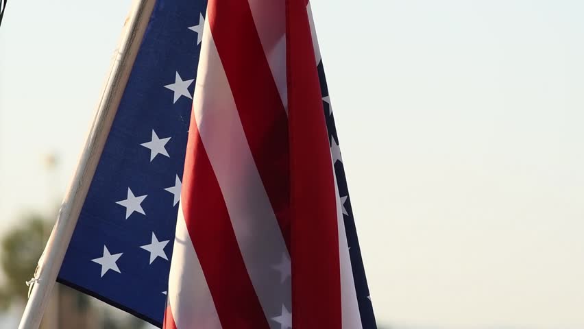 Close-up background of a US flag waving at sunset. Patriotic national symbol of unity and freedom. Flag Day, American holidays, Independence Day, 4 of July