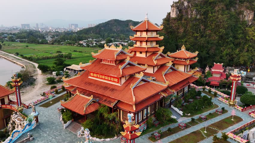 Aerial view of quan the am pagoda at sunset in the marble mountains of da nang, vietnam with city landscape in background.
