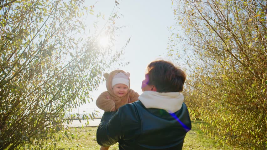 Joyful Parent-Child Moment: A Parent Lifts Their Happy Child in a Cute Animal Outfit Surrounded by Nature, Expressing Love and Delight in the Sunshine.