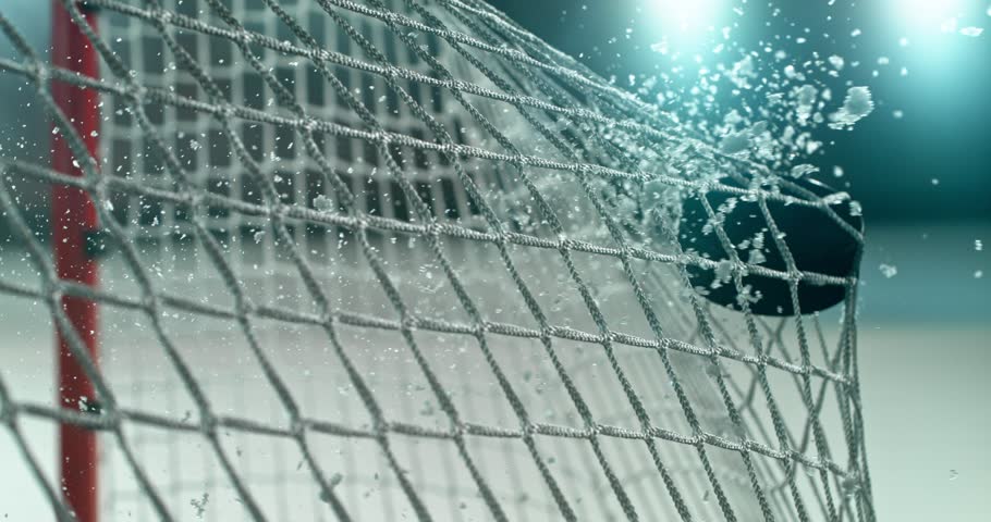 Extreme super slow motion close-up of an ice hockey puck striking the goal net at 1000 fps, with ice particles exploding on impact and a blurred winter stadium and rink in the background.