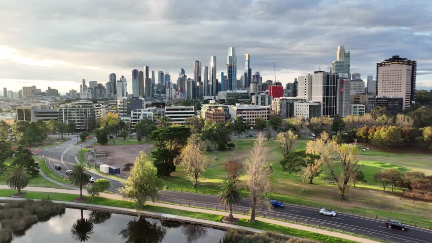 Drone Flight Above Albert Park with Scenic View of Melbourne Skyline on Cloudy Day