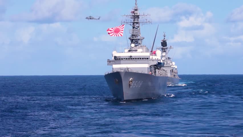 Japanese naval destroyers sail forward in close formation during coordinated maritime patrol exercise at sea.
