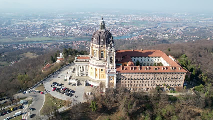 Aerial drone view of the majestic Basilica of Superga and its monastery buildings on the hilltop in Turin, Italy, historic baroque architecture, city panorama, sunny daylight.